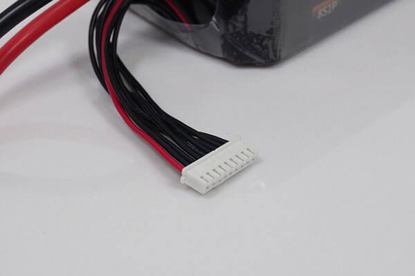 A close-up shot of a balance charger connected to the balance plug of a 6S LiPo battery, with the charger's screen showing the individual cell voltages.